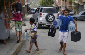TO GO WITH AFP STORY by Gerardo Guarache Boys carry empty bottles and cans to fill them with water in Caucaguita, Caracas, on June 20, 2014. Water use in Caracas and its suburbs, home to five million people, is being rationed since the beginning of May and will continue for two more months, due to drought. Even when fully operating and unaffected by drought, water supply levels in the capital area are below international standards, capable of providing 340 liters per person per day, which is sufficient for household consumption but falls short of commercial and industrial demands. AFP PHOTO/Leo RAMIREZ
